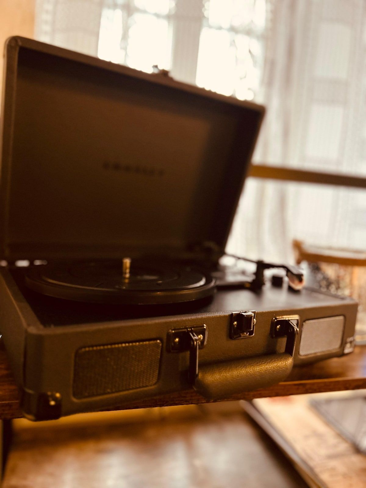 A vintage turntable with a leather case, placed on a wooden surface.