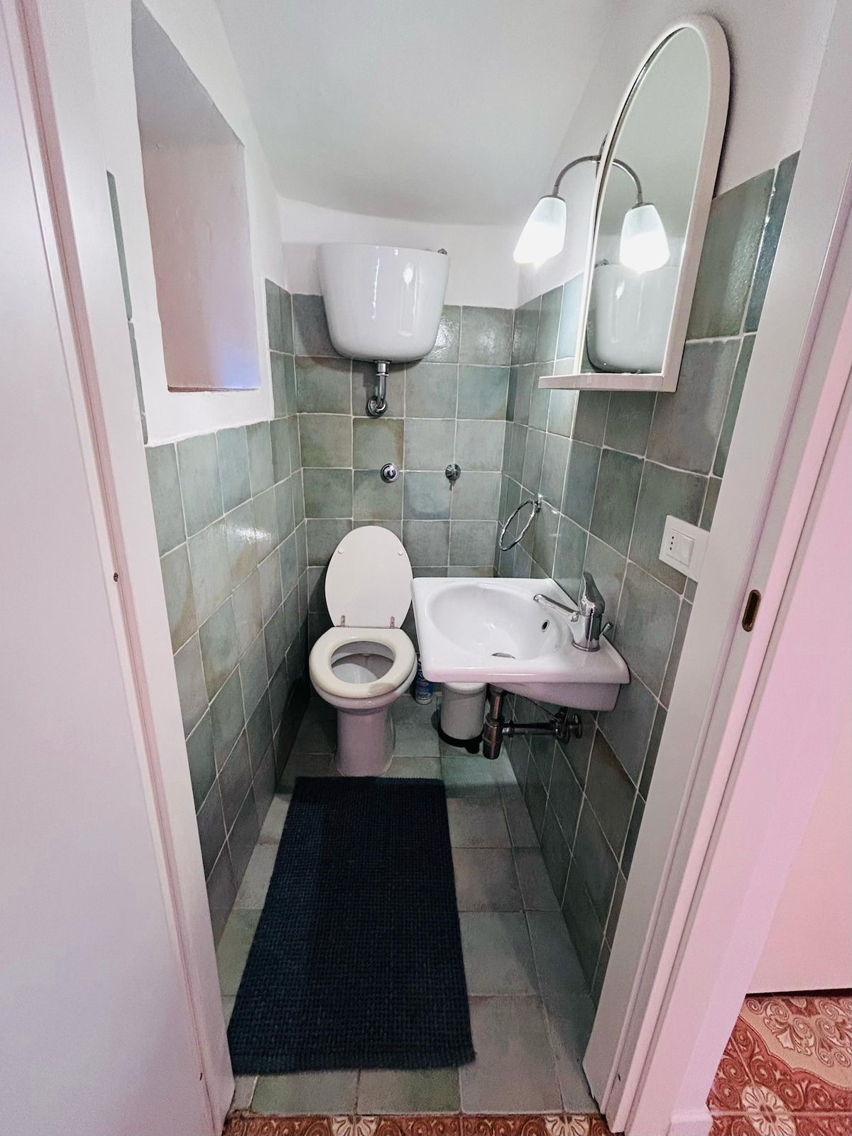 A small bathroom with a toilet, sink, and mirror.