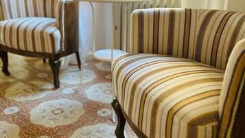 Ein Zimmer mit zwei gestreiften Sesseln, einem kleinen runden Tisch und einer Heizung.