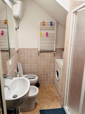 Ein kleines Badezimmer mit Toilette, Waschbecken und Waschmaschine.