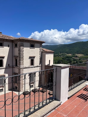 Un bâtiment doté d’un toit en tuiles, de murs en pierre et d’un balcon avec une rambarde en métal.