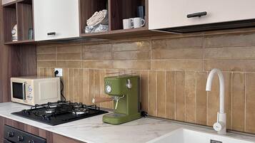 A kitchen with a microwave, stove, coffee maker, and a sink.