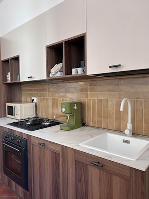 A kitchen with a microwave, stove, coffee maker, and a sink.