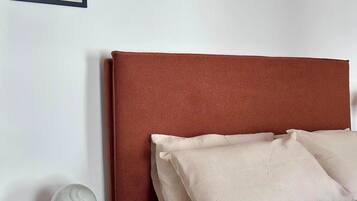 A bedroom with a bed, pillows, a nightstand, a framed picture, and a lamp.