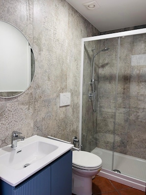 A bathroom with a shower, toilet, and sink.