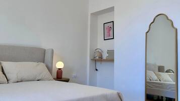 Ein Schlafzimmer mit Bett, Nachttischlampe, einer Wandablage und einem großen Spiegel.
