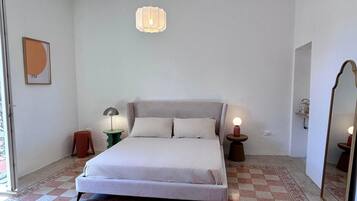 Una camera da letto con un letto, due comodini, una lampada a sospensione e un tappeto decorato.