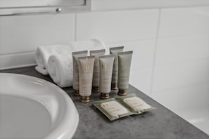 Ein Badezimmer mit einem weißen Waschbecken, einem Handtuch und mehreren Kosmetikprodukten in Tuben und Beuteln auf der Ablagefläche.