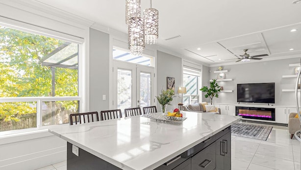 A modern kitchen with a large island, built-in appliances, and a dining area with chairs.