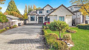 A two-story house with a paved driveway and a well-maintained lawn.