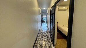 A narrow hallway with patterned flooring, leading to a room with a bed and an air conditioning unit. - Phukhao Hostel (Chiang Mai)