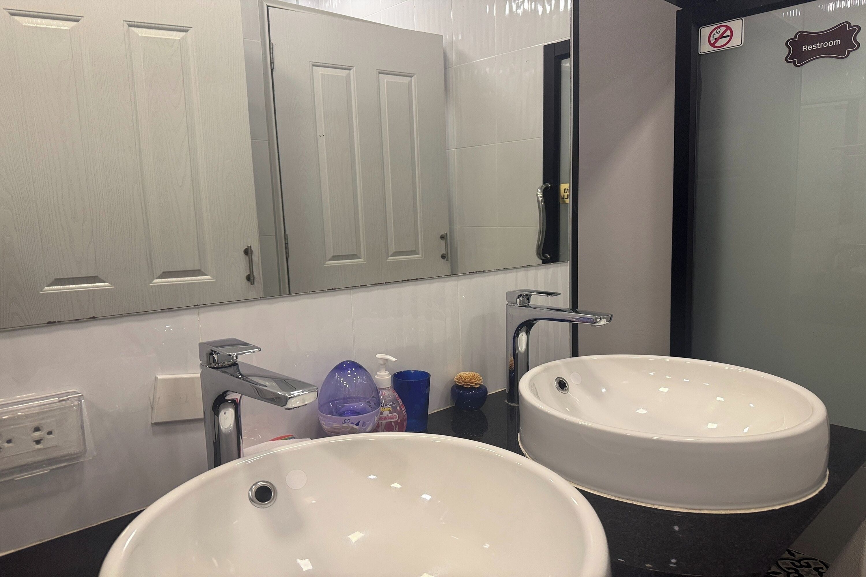 A bathroom with two sinks, a mirror, and a door marked "Restroom".