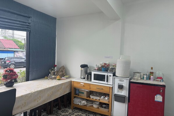 Cocina compacta con microondas, refrigerador y un mueble pequeño con varios objetos.