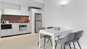 A modern kitchen with white cabinets, a built-in oven, and a stainless steel refrigerator. - Modern 1-bed City Apartment With Pool and Gym (Melbourne)