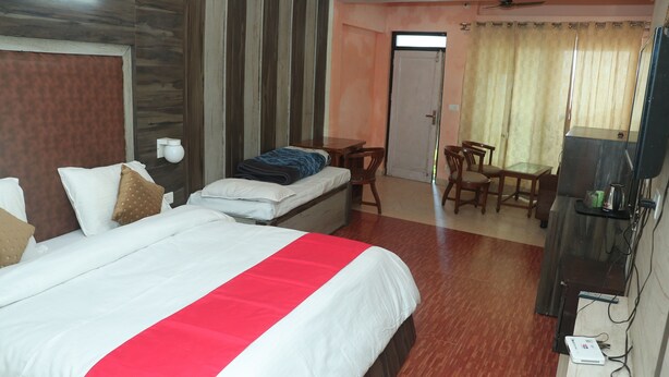 A hotel room with a large bed, a desk, a chair, and a television. - Krishna Hotel And Restaurant (Dharamshala)