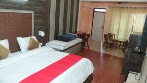 A hotel room with a large bed, a desk, a chair, and a television. - Krishna Hotel And Restaurant (Dharamshala)
