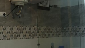 A bathroom with a toilet, a shower, and a water heater. - Krishna Hotel And Restaurant (Dharamshala)