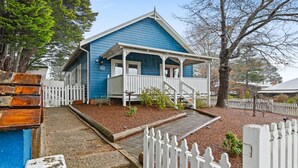 A blue house with a porch, white picket fence, and a small garden area. - Bright 3-bed House With Garden, (Blackheath)