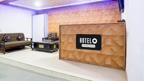 Ein Hotel-Empfangsbereich mit Holztresen, einer Couch und einem Couchtisch.