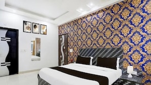 Ein modernes Hotelzimmer mit einem großen Bett, einem gemusterten Wandteppich und einem dekorativen Spiegel.