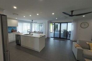 Una cocina moderna con una isla central, un área de comedor con sofá y un amplio ventanal corredero que da a un balcón.