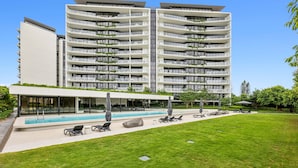 A modern hotel with a central swimming pool, outdoor seating, and a well-maintained lawn. - Glorious Ocean Views, 2-bed, Pool & Amenities (Gold Coast)
