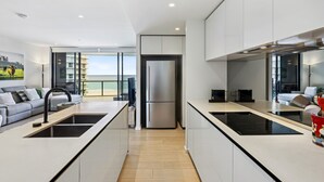 A modern kitchen with a central island, a built-in oven, and a view to the outside. - Glorious Ocean Views, 2-bed, Pool & Amenities (Gold Coast)