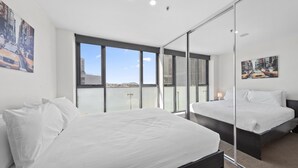 Un dormitorio moderno con una cama grande, un muro de vidrio y vistas a la ciudad.