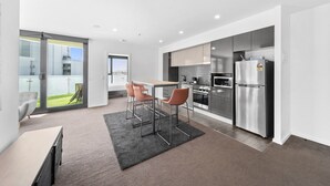 Una cocina moderna con electrodomésticos de acero inoxidable, un comedor con mesa y sillas, y un amplio ventanal corredero que da a un balcón.
