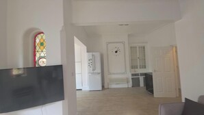 Un pasillo con un refrigerador blanco, un reloj y una puerta que da a otra habitación.