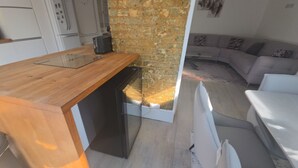Una cocina con encimera de madera, pared de ladrillo y vista a una sala de estar con sofá y alfombra.