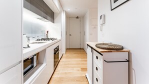 Eine schmale Küche mit weißen Schränken, einer Holz Arbeitsplatte und einer kleinen Kücheninsel mit einem gewobenen Platzdeckchen.