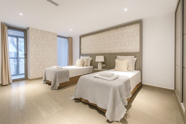 A hotel room with two beds, a large window, and a modern design. - Joli Appartement a Sidi Yahia (Algiers)