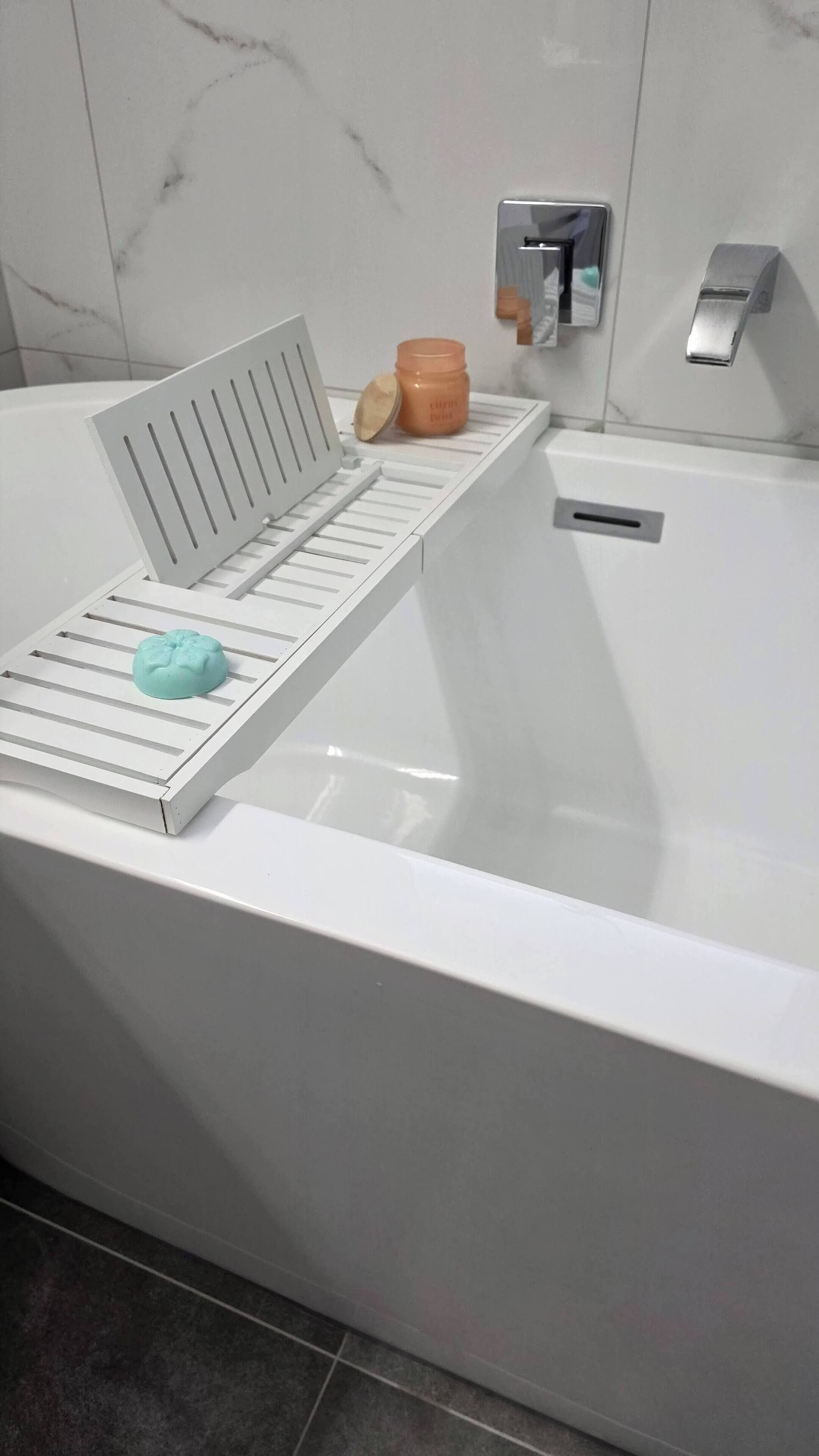 A bathroom with a white bathtub, a white shelf with a towel and a jar, and a faucet.