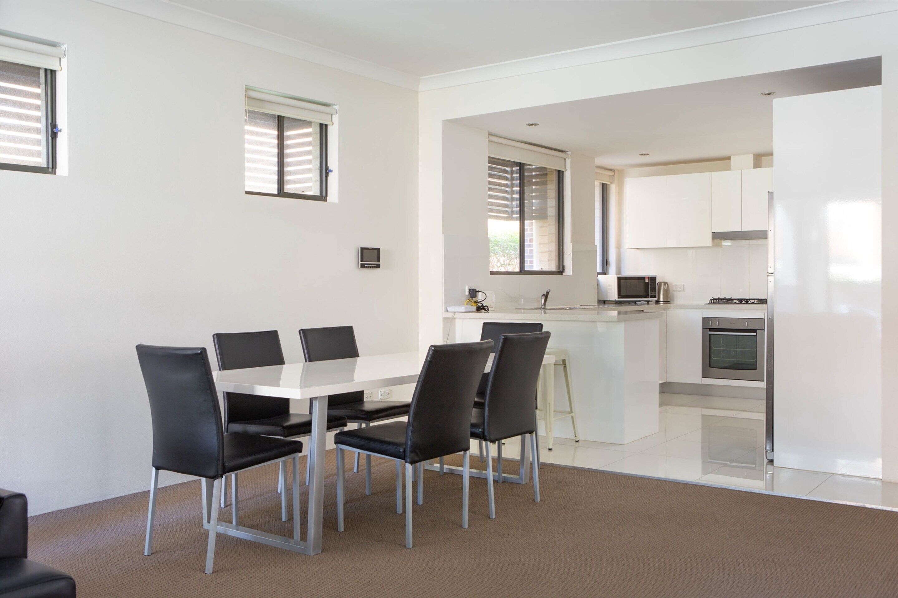 A modern kitchen with white cabinets, a microwave, and an oven.