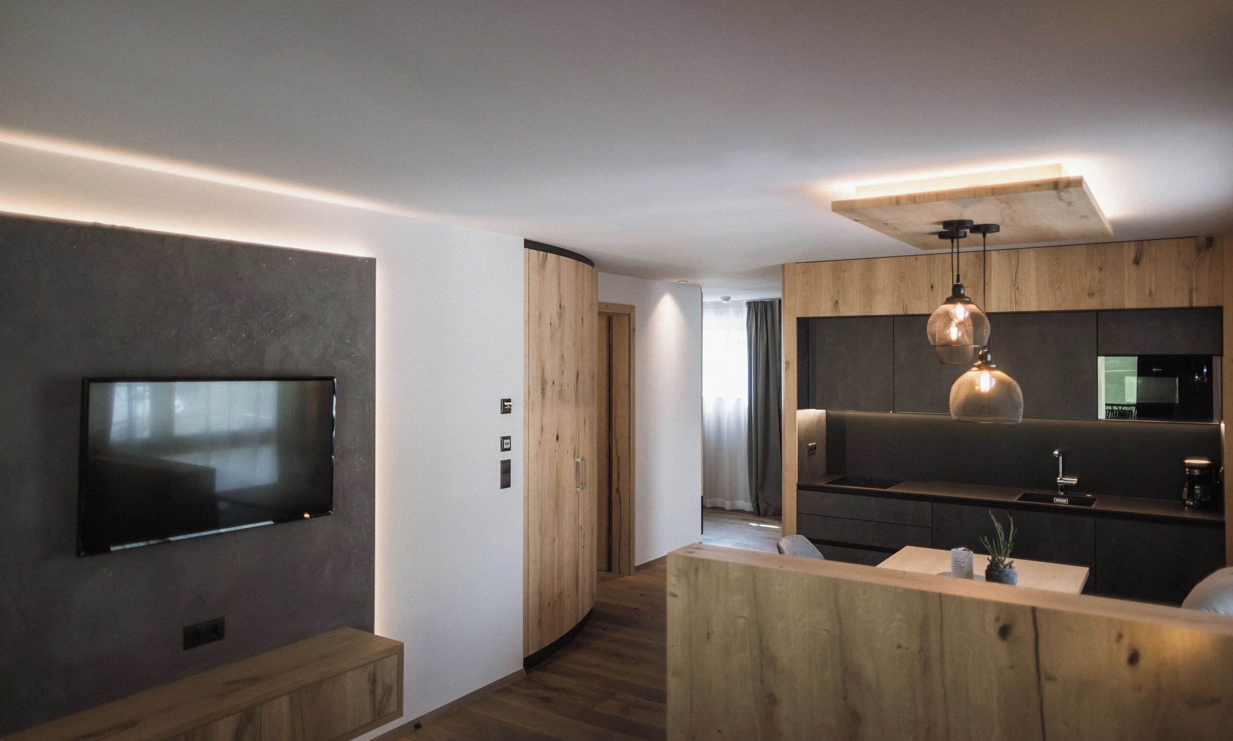 Una cocina moderna con horno empotrado, encimera de madera e iluminación colgante.
