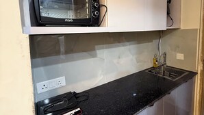 A kitchen with a built-in microwave, a countertop with a power strip, and a sink. - Charming bed & breakfast in enchanting Greater Noida with AC (Greater Noida)