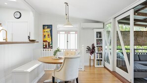 Une cuisine moderne avec un plan de travail en bois, une table à manger avec des chaises, un luminaire suspendu et une bibliothèque.