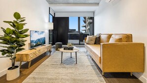 Una sala moderna con sofá, mesa de centro, televisor y una planta.