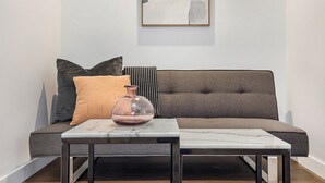 Una sala moderna con un sofá gris, una mesa de centro de mármol y un florero.
