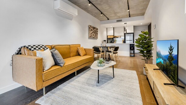 Una sala de estar moderna con un sofá, una mesa de centro y un televisor sobre un mueble de madera.