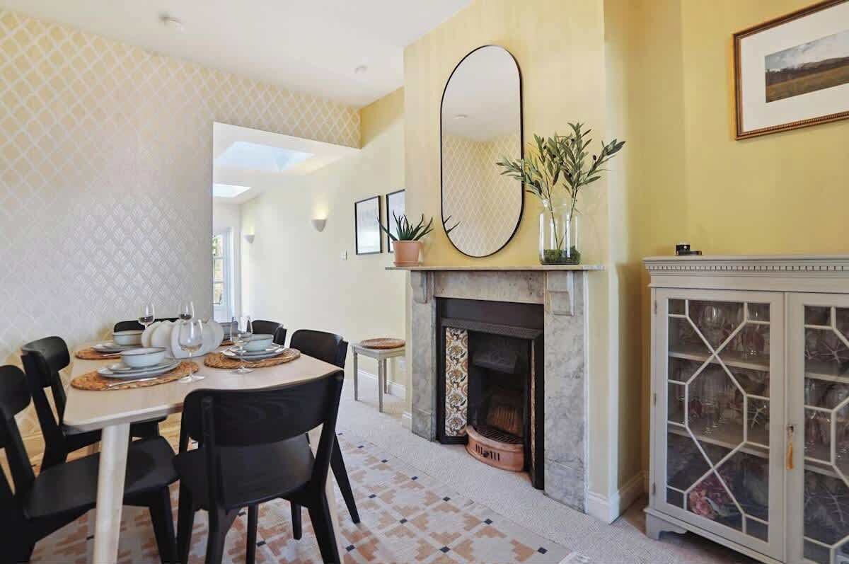 A dining area with a round table, black chairs, a fireplace, and a cabinet with glass doors.