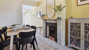 Un coin repas comprenant une table ronde, des chaises noires, une cheminée et un meuble avec des portes en verre.