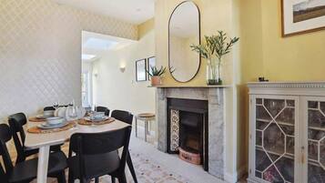 A dining area with a round table, black chairs, a fireplace, and a cabinet with glass doors.
