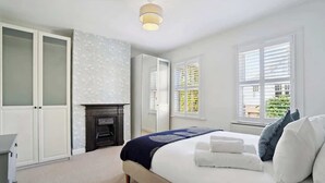 Une chambre à coucher avec un lit, une armoire, un miroir, une cheminée et des fenêtres.