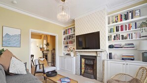 Un salon avec une cheminée, des étagères à livres, un téléviseur et un canapé.