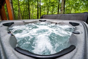A hot tub with water jets in a forested area.