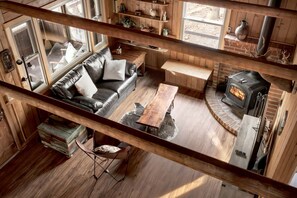 A cozy cabin interior with a leather sofa, a wooden table, and a fireplace.