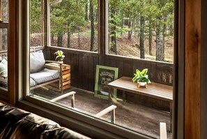 A cozy seating area with a bench and a cushioned chair, a wooden table with a potted plant, and a welcome sign.