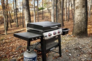 A portable grill with a side table and a propane tank.